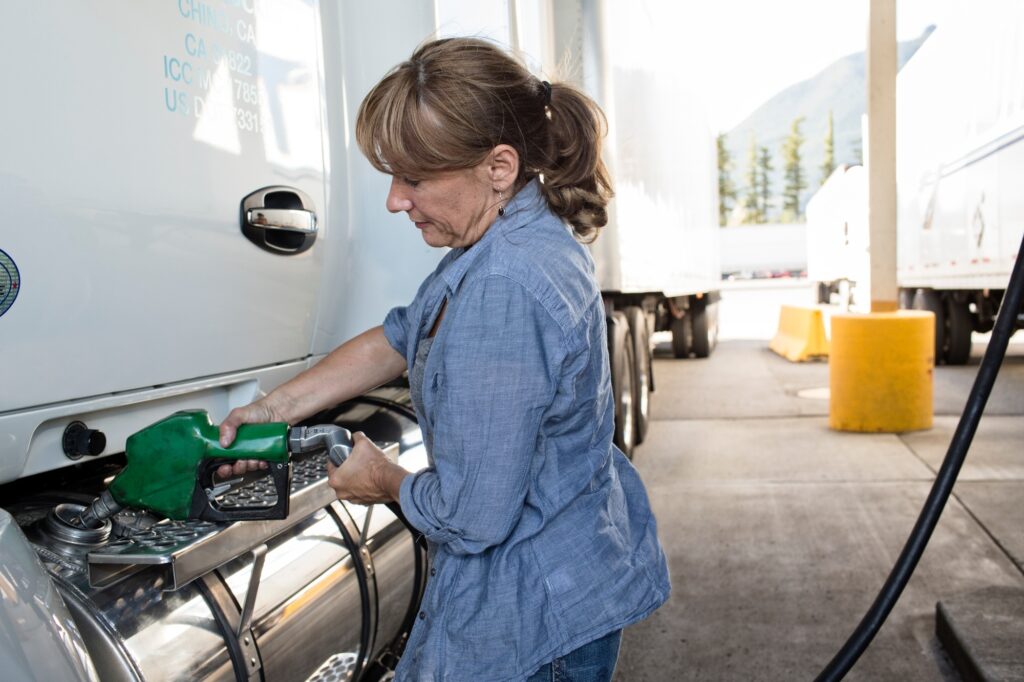 Caucasian woman truck driver filling truck with diesel fuel at a truck stop.