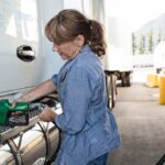 Caucasian woman truck driver filling truck with diesel fuel at a truck stop.