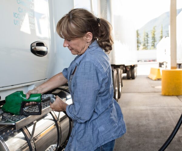 Caucasian woman truck driver filling truck with diesel fuel at a truck stop.
