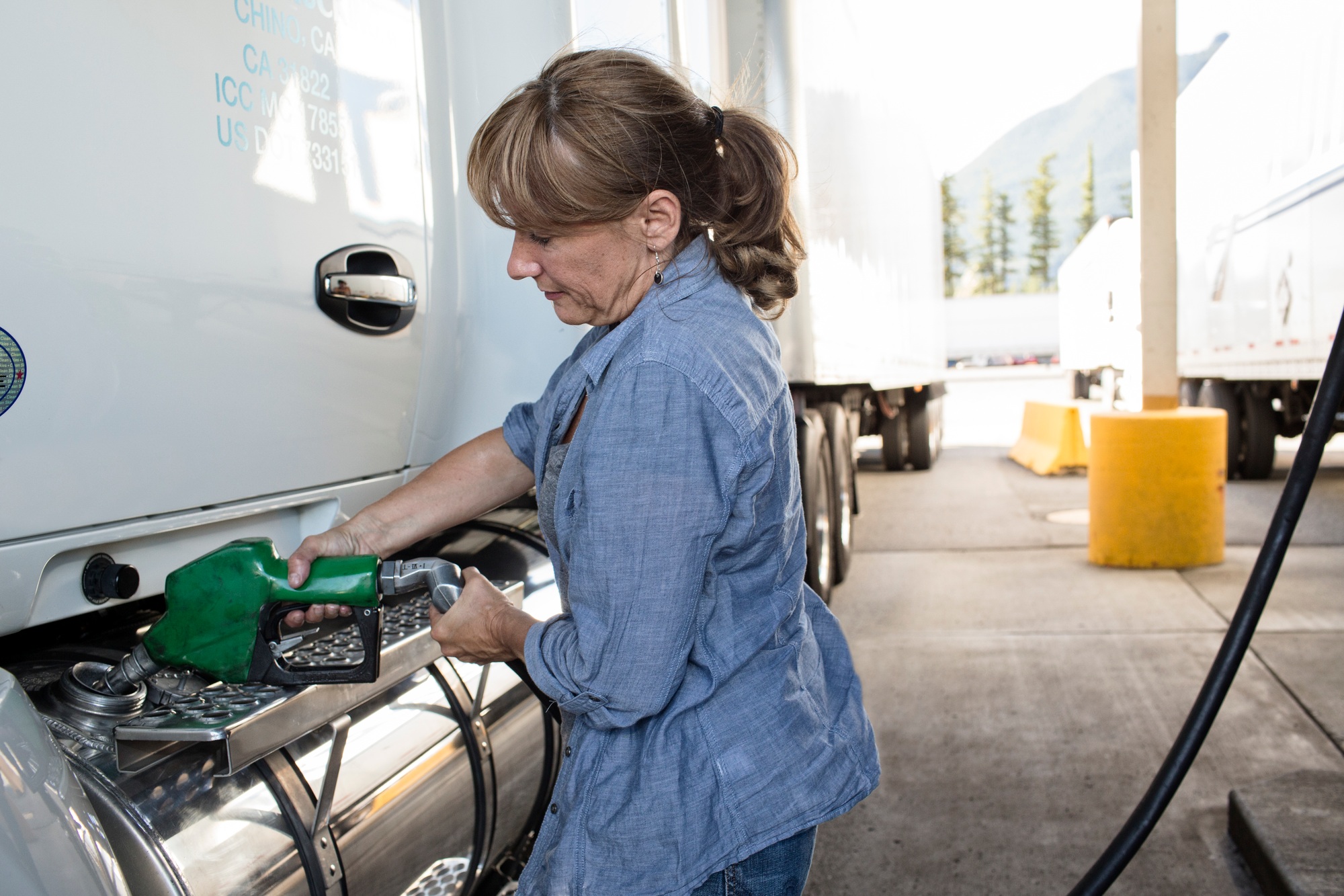 Caucasian woman truck driver filling truck with diesel fuel at a truck stop.